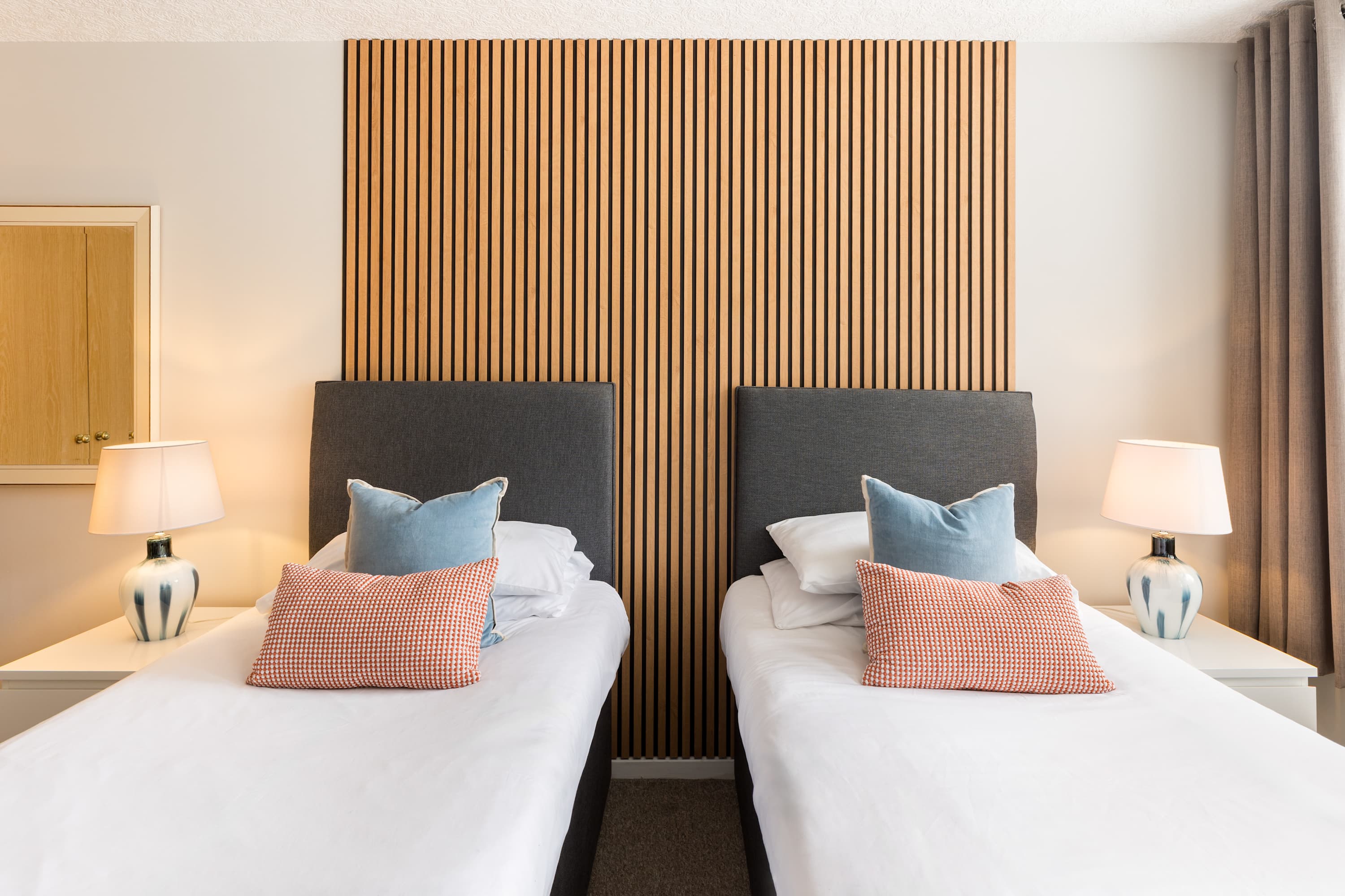 A twin bedroom with a slatted wood wall in a Leamington Spa apartment