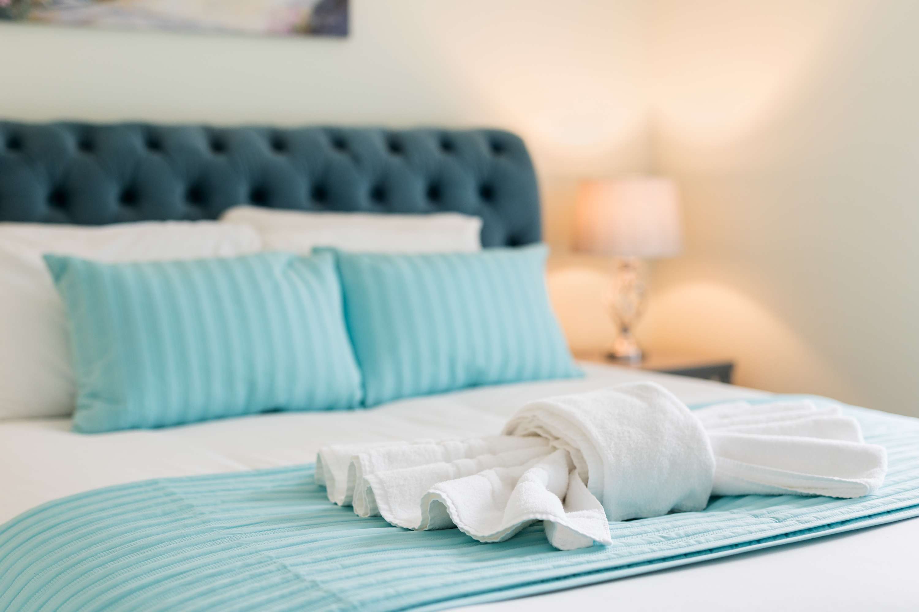 A freshly made bed with folded towels, ready for the next guest